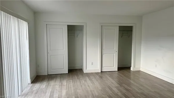 an empty room with wooden floor and closet area