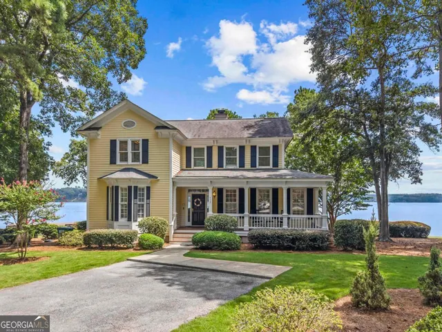 a front view of a house with garden and trees