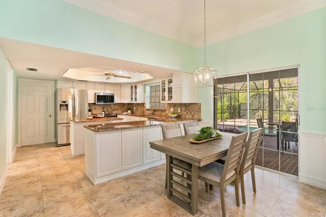 a kitchen with kitchen island granite countertop a stove a sink a dining table chairs and view living room