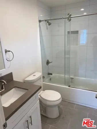 a bathroom with a granite countertop bathtub shower sink vanity and toilet