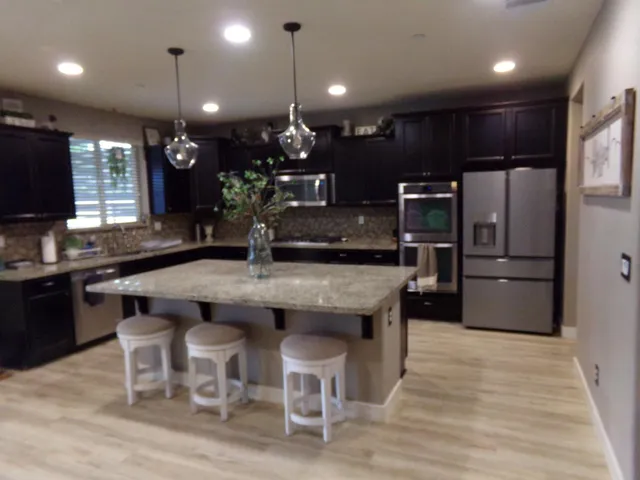 a kitchen with granite countertop kitchen island stainless steel appliances a sink and a refrigerator
