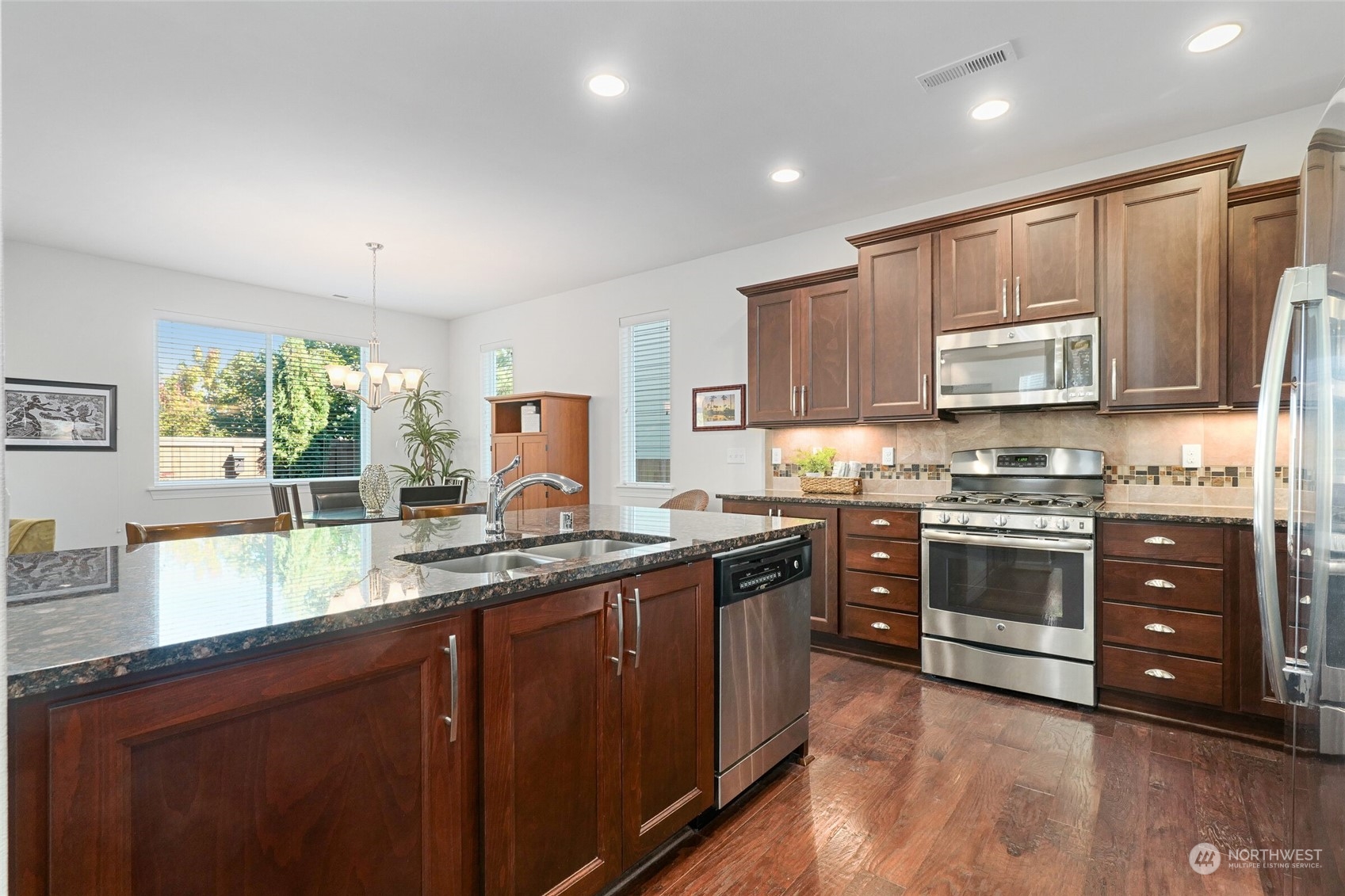 3533 198th Street Southeast Bothell, WA 98012 - Photo 12 of 27 a kitchen with stainless steel appliances granite countertop wooden cabinets a stove a sink and dishwasher with wooden floor