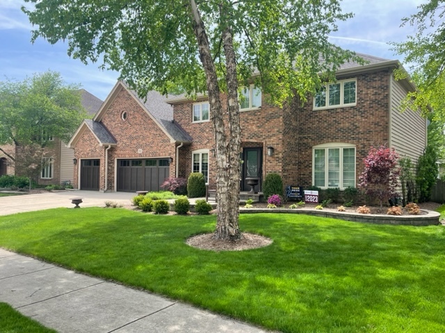 a front view of a house with a garden and trees
