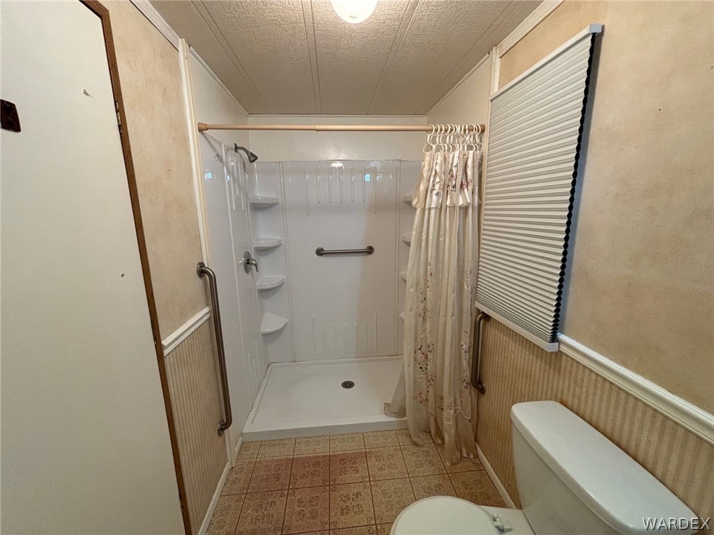 3565 Ehrenberg Road Golden Valley, AZ 86413 - Photo 32 of 63 a bathroom with a glass door shower and toilet