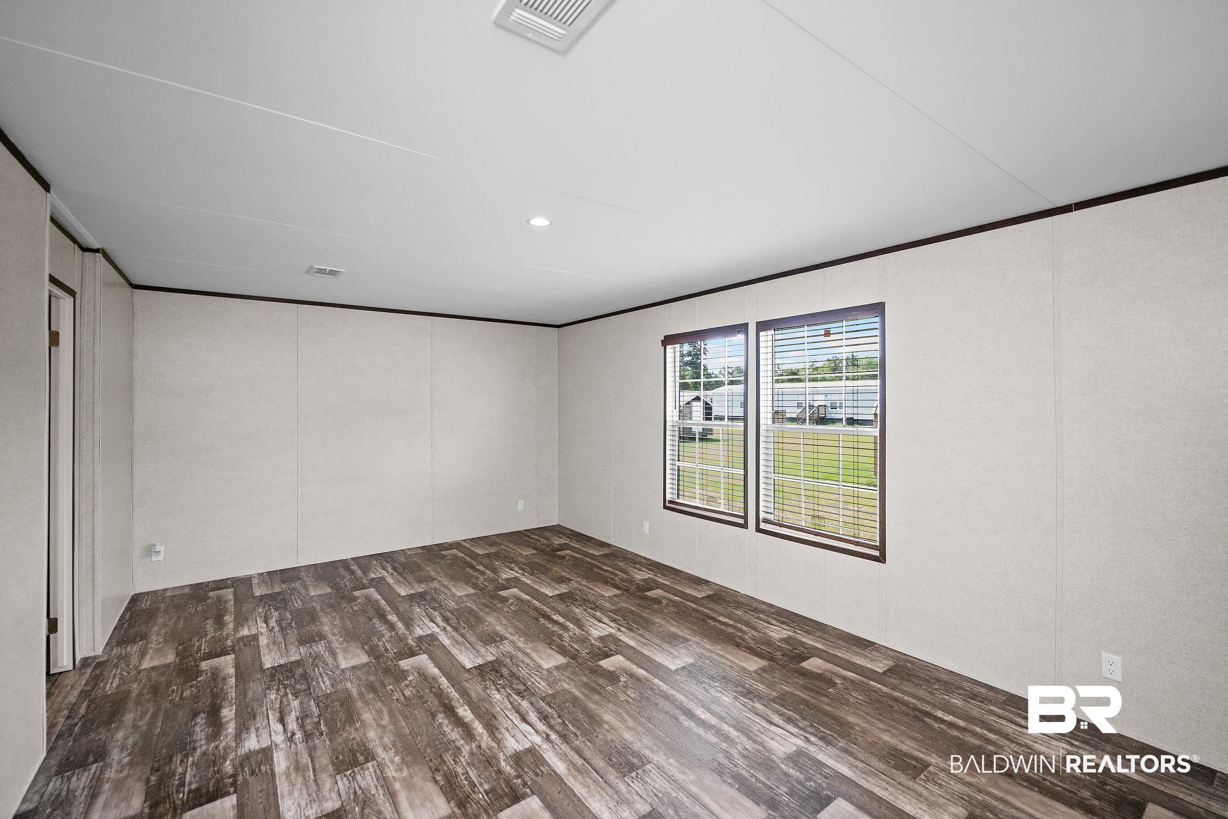 21601 Westside Loop Silverhill, AL 36576 - Photo 18 of 42 Spacious interior room featuring wood-finish flooring, two large windows with blinds, a recessed ceiling light, and white paneled walls with dark trim