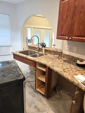 a room with stainless steel appliances kitchen island granite countertop a sink dishwasher stove and cabinets