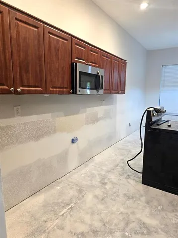 a kitchen with stainless steel appliances granite countertop a sink a stove a refrigerator cabinets a dining table and chairs