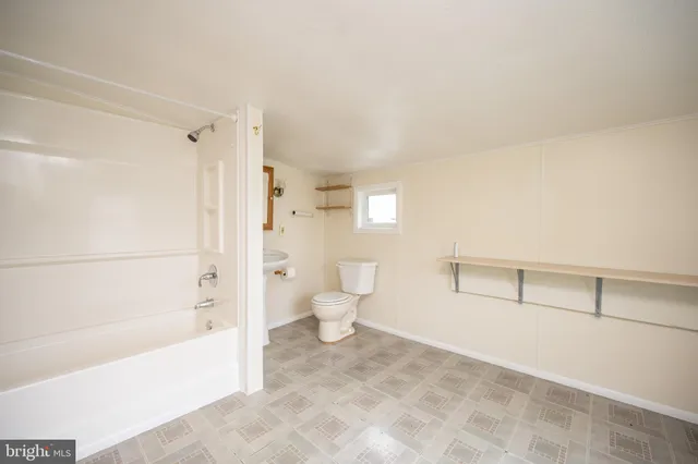 a view of an empty room with a window and bathroom