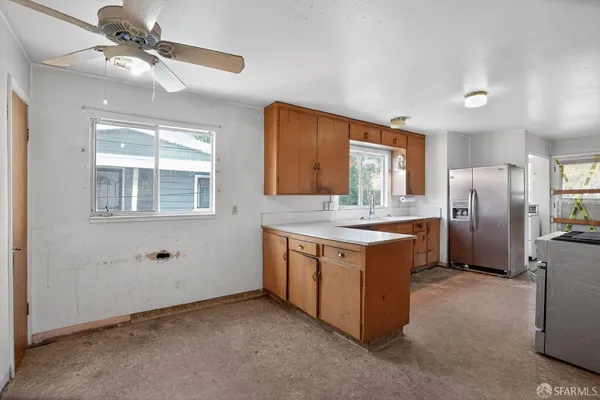 a kitchen with stainless steel appliances granite countertop a refrigerator a sink a stove a washer dryer and white cabinets