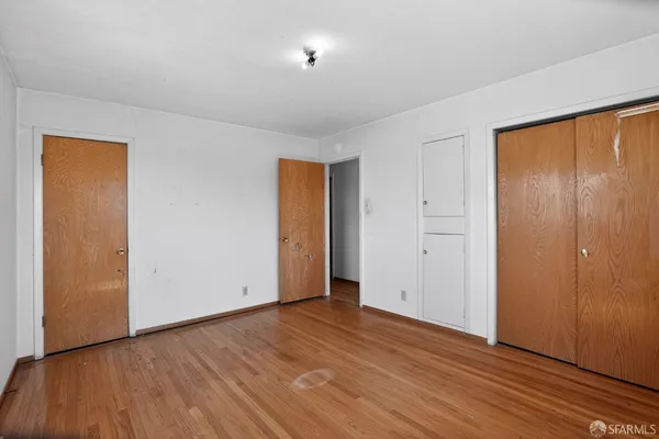 a view of an empty room with wooden floor and closet