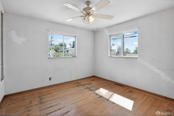 a view of an empty room with window and wooden floor