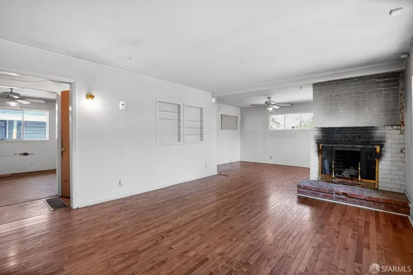 an empty room with wooden floor and fireplace