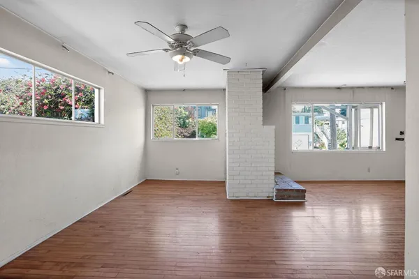 an empty room with wooden floor chandelier and windows