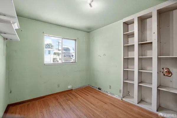 a view of empty room with wooden floor and fan