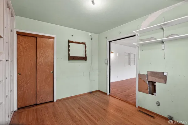 a view of an empty room with wooden floor and a bathroom