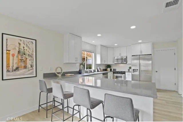 a kitchen with stainless steel appliances granite countertop a dining table chairs and refrigerator