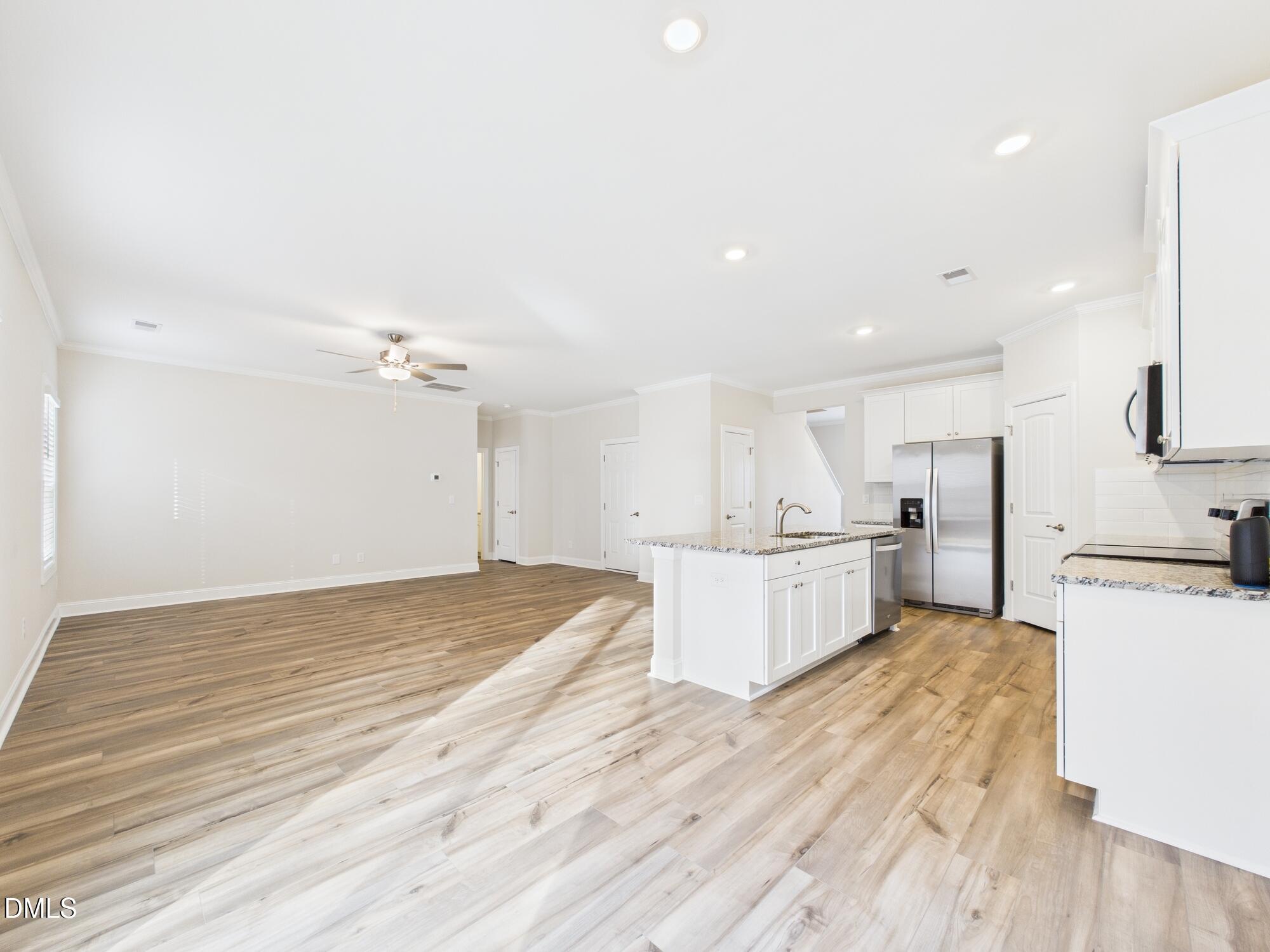 110 Symmetry Loop Youngsville, NC 27596 - Photo 24 of 72 a large kitchen with kitchen island a stove a sink dishwasher a refrigerator and white cabinets with wooden floor