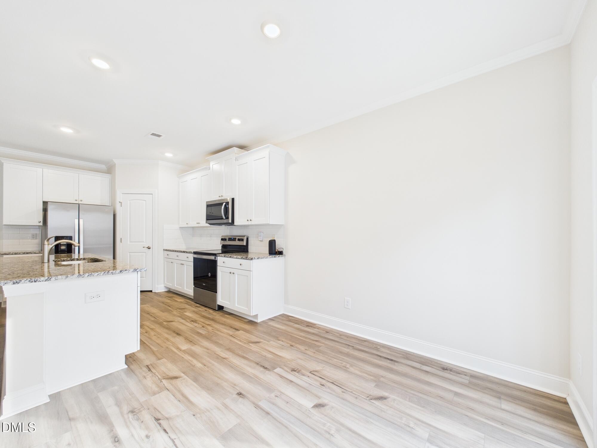 110 Symmetry Loop Youngsville, NC 27596 - Photo 25 of 72 a large kitchen with granite countertop a large counter top stainless steel appliances and cabinets