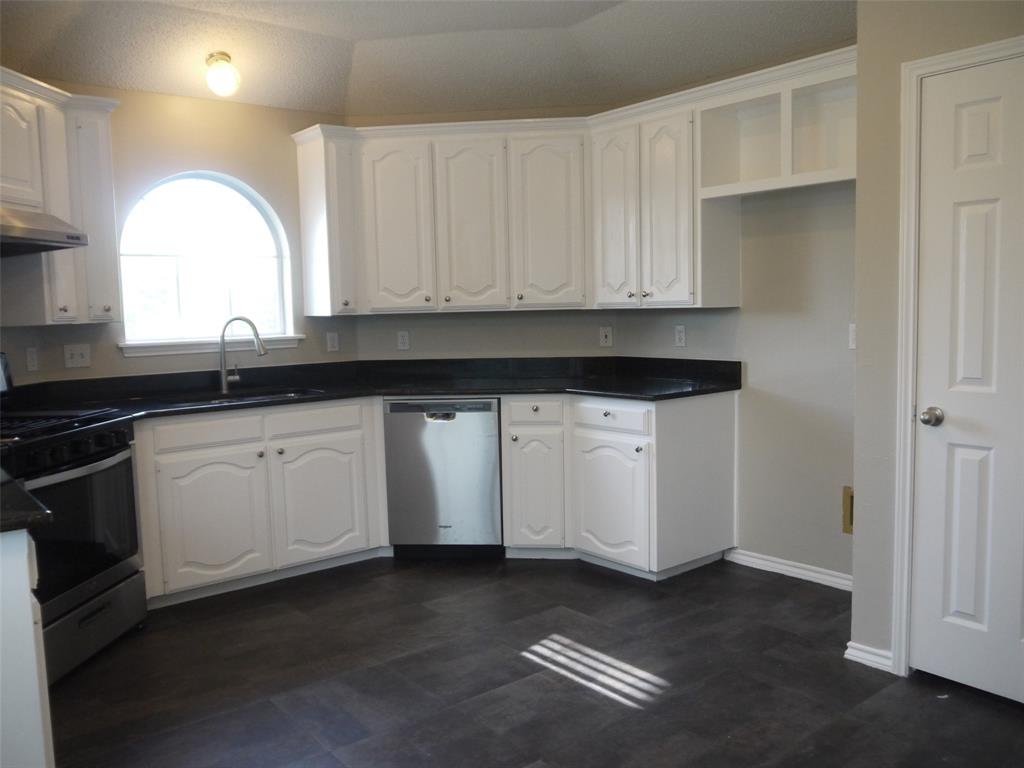 10931 Castle Drive Frisco, TX 75035 - Photo 7 of 14 a kitchen with granite countertop white cabinets and sink