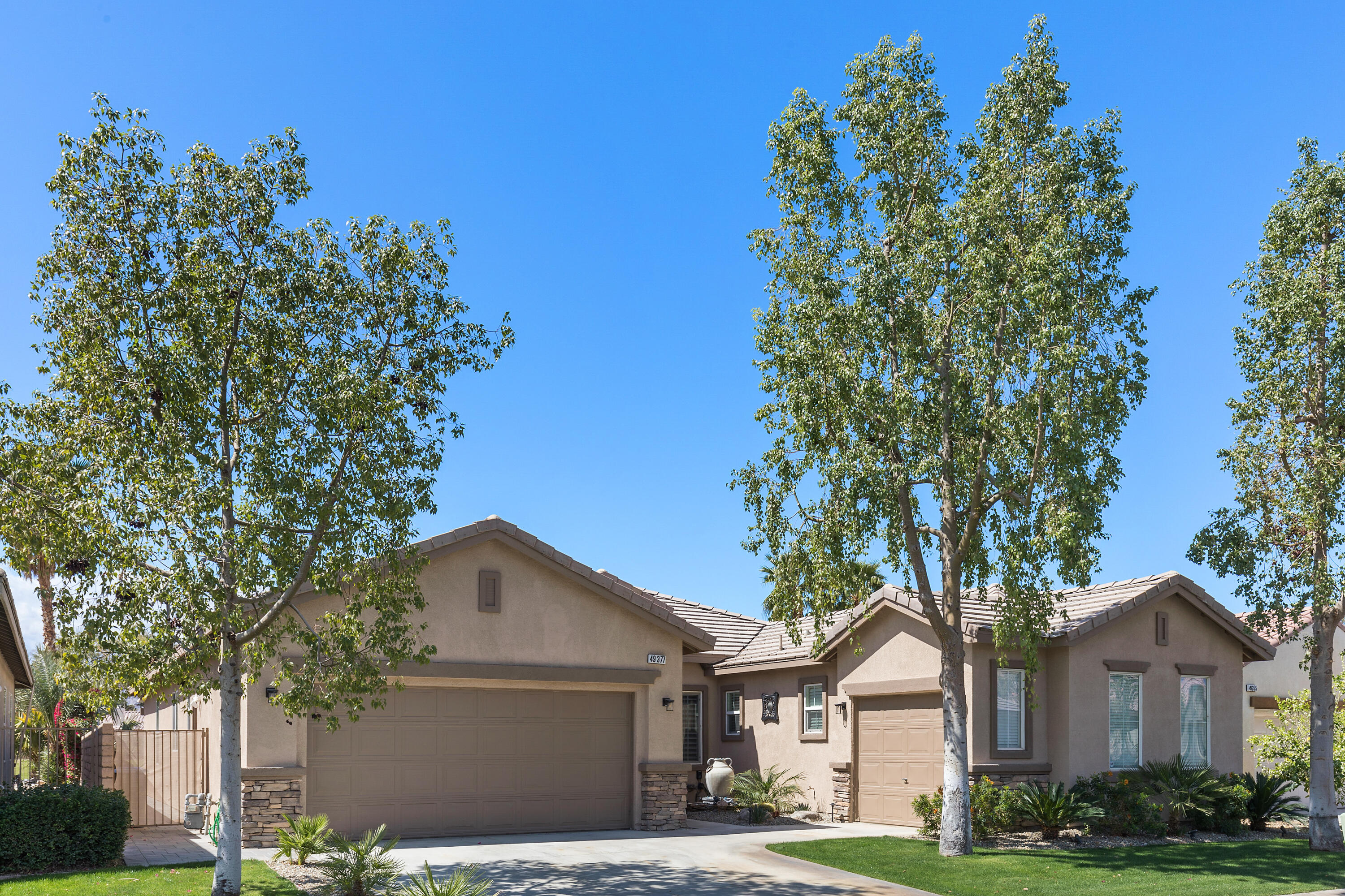 49377 Biery Street Indio, CA 92201 - Photo 2 of 32 a front view of a house with a garden and trees