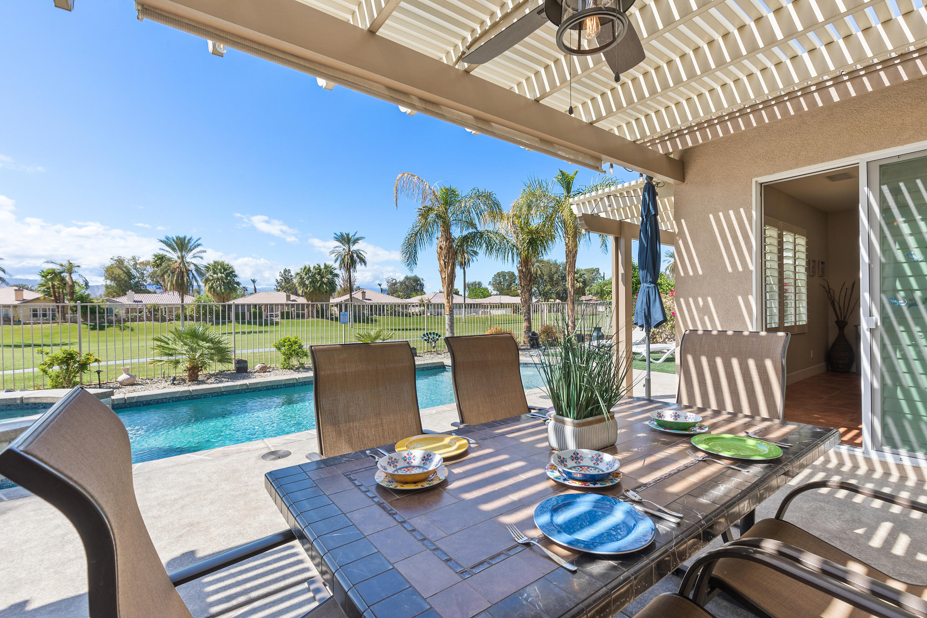 49377 Biery Street Indio, CA 92201 - Photo 24 of 32 a view of a patio with chairs and table potted plants and floor to ceiling window