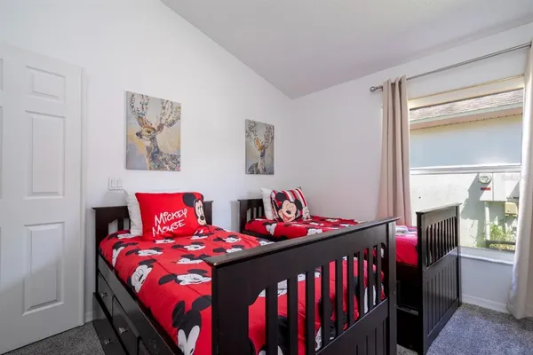 a bedroom with two beds and next to a window