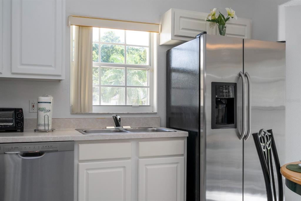 4669 Prairie Point Boulevard Kissimmee, FL 34746 - Photo 10 of 13 a kitchen with stainless steel appliances granite countertop a refrigerator a sink a stove and white cabinets with wooden floor