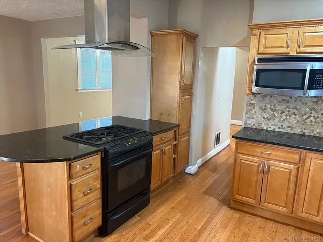 a kitchen with stainless steel appliances granite countertop a stove a refrigerator and a wooden cabinets