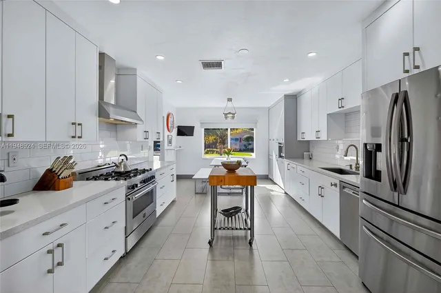 a kitchen with stainless steel appliances granite countertop a stove top oven a sink dishwasher and a refrigerator