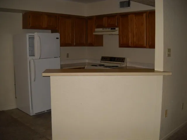 a close view of a refrigerator a sink and wooden cabinets