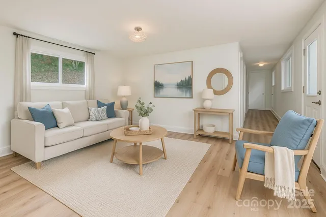 a living room with furniture a clock on wall and a window