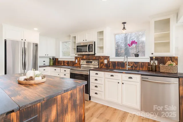 a kitchen with stainless steel appliances kitchen island granite countertop a sink dishwasher and cabinets with wooden floor