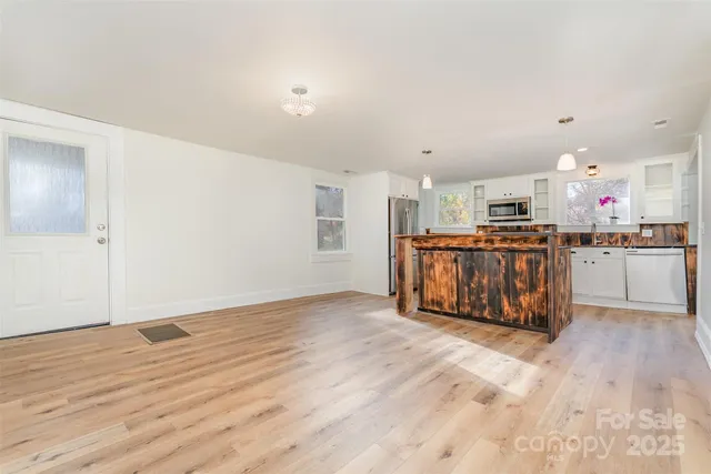 a large white kitchen with wooden floors and stainless steel appliances