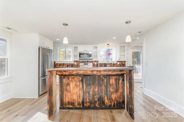 a kitchen with stainless steel appliances kitchen island granite countertop a refrigerator a stove a sink and a microwave with wooden floor