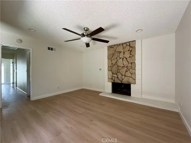 an empty room with wooden floor a ceiling fan and windows