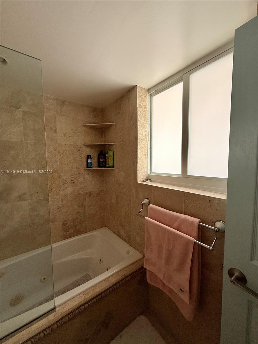 180 Isle Of Venice Drive, Unit 100 Fort Lauderdale, FL 33301 - Photo 11 of 16 a bathroom with a bathtub and a shower