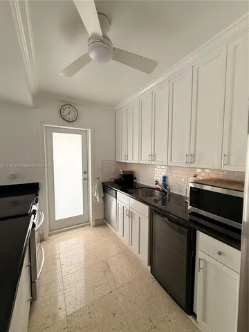 a kitchen with granite countertop a sink dishwasher stove and white cabinets