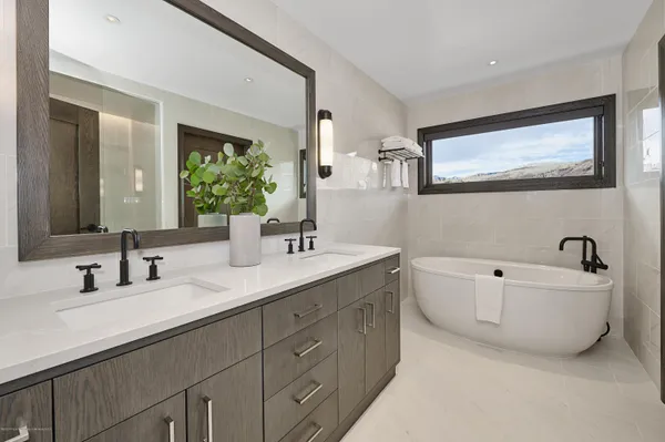 a bathroom with a double vanity sink mirror and bathtub