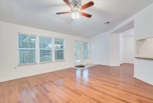 a view of an empty room with window and wooden floor