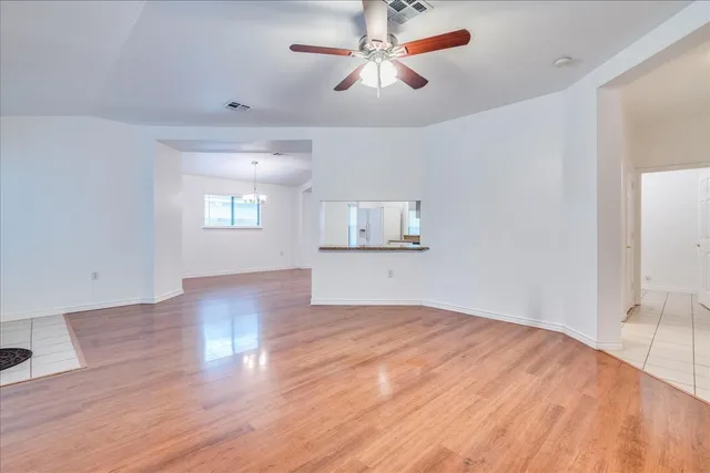 a view of empty room with wooden floor and fan