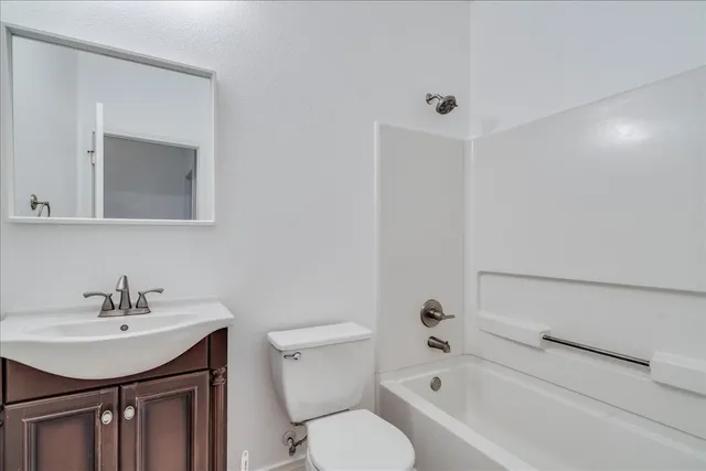 a bathroom with a bathtub shower sink vanity mirror and toilet