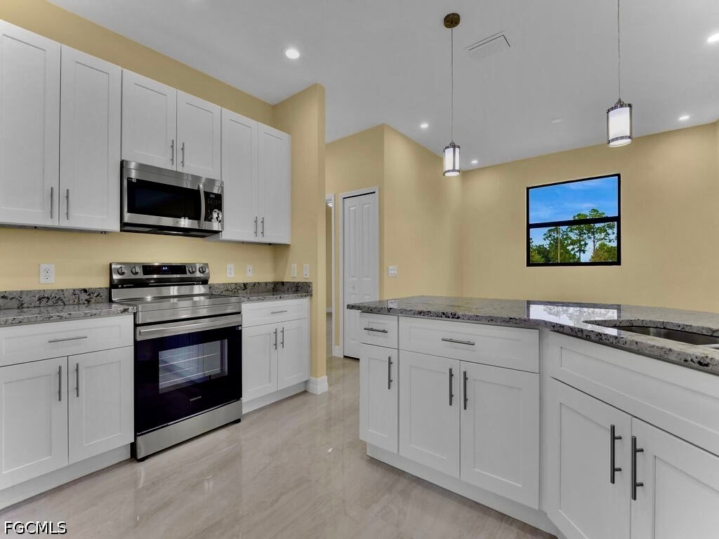 637 Cardinal Street East Lehigh Acres, FL 33974 - Photo 26 of 34 a kitchen with white cabinets and stainless steel appliances