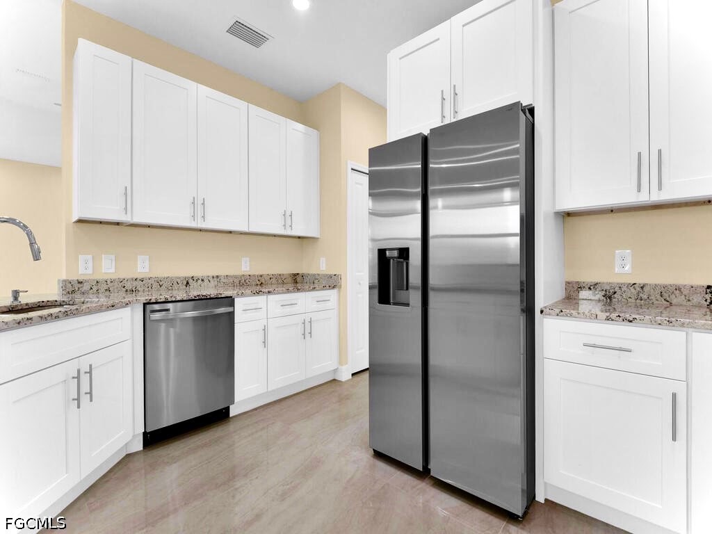 637 Cardinal Street East Lehigh Acres, FL 33974 - Photo 27 of 34 a kitchen with granite countertop white cabinets and stainless steel appliances