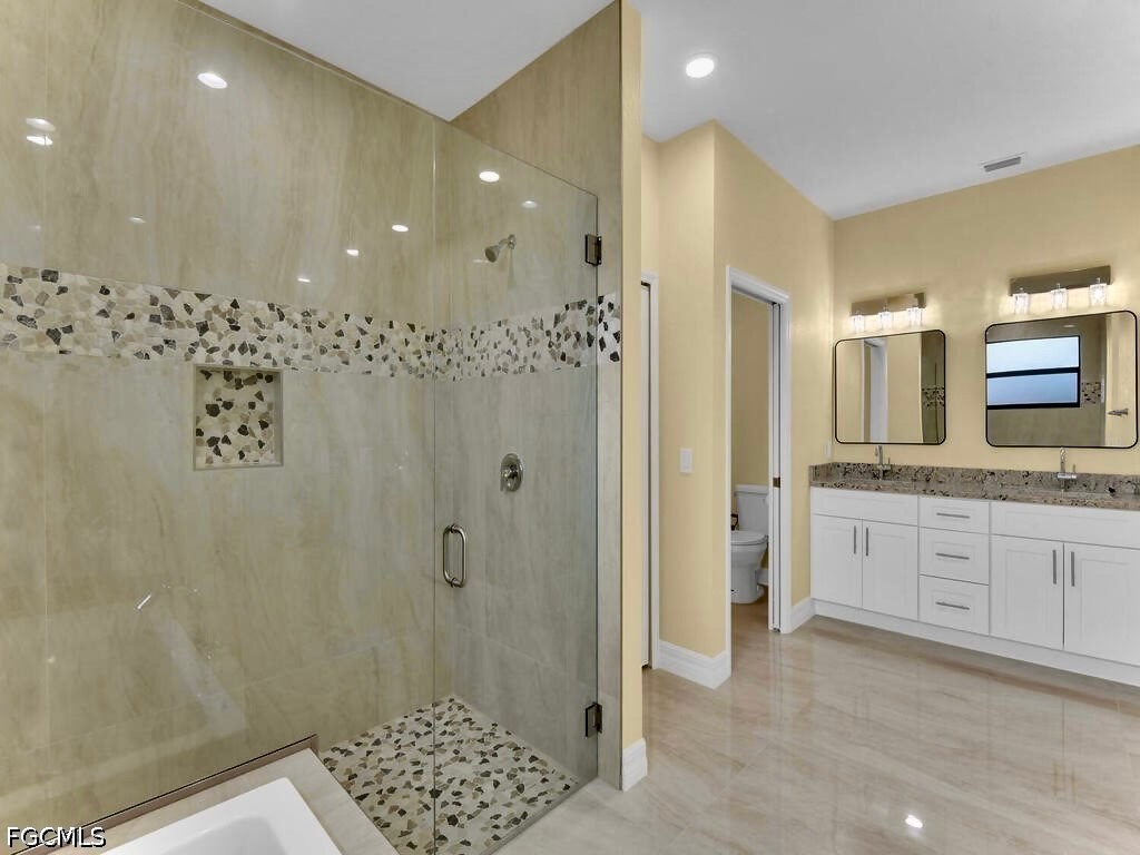 637 Cardinal Street East Lehigh Acres, FL 33974 - Photo 10 of 34 a bathroom with a granite countertop sink a mirror a vanity and a shower