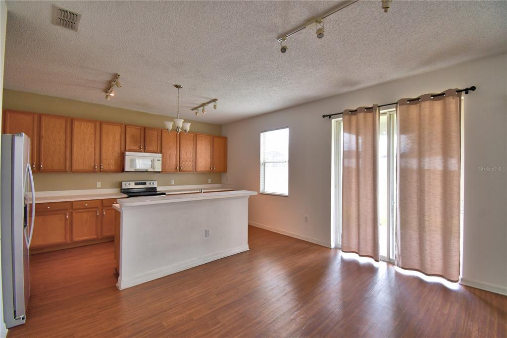 154 Canna Drive Davenport, FL 33897 - Photo 27 of 85 a kitchen with stainless steel appliances granite countertop a refrigerator a sink dishwasher a stove and white countertops with wooden floor