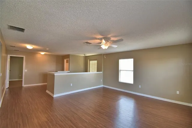 an empty room with a window and ceiling fan