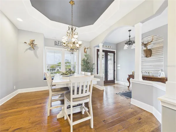 a dining room with wooden floor a chandelier a wooden table and chairs