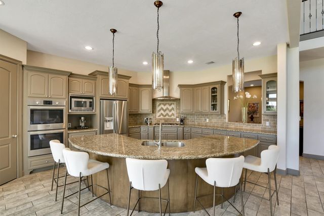 a kitchen with granite countertop kitchen island stainless steel appliances a dining table chairs sink and stove