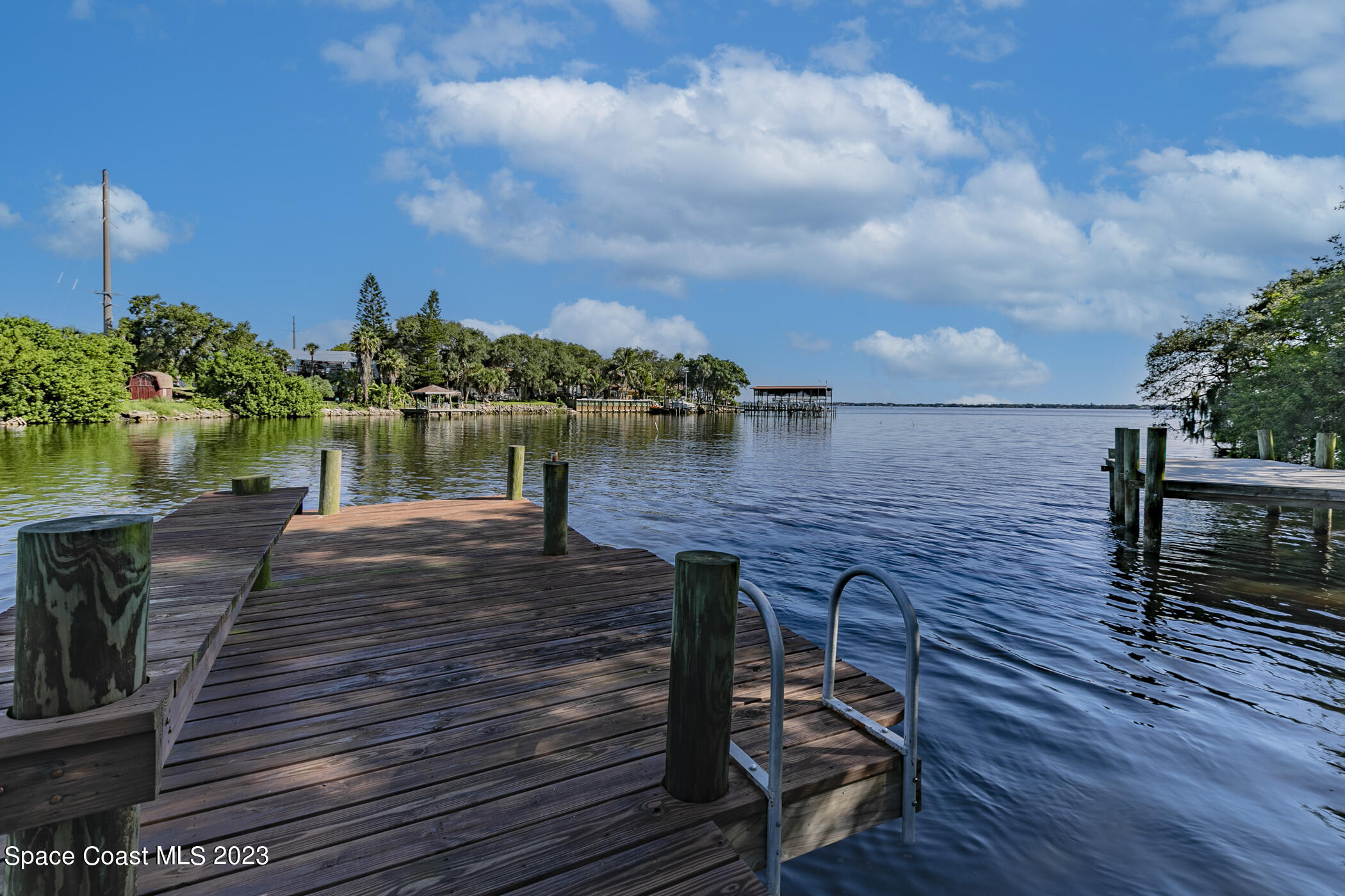 1428 Rose Court Melbourne, FL 32935 - Photo 71 of 78 a view of a wooden deck and lake with trees in the background