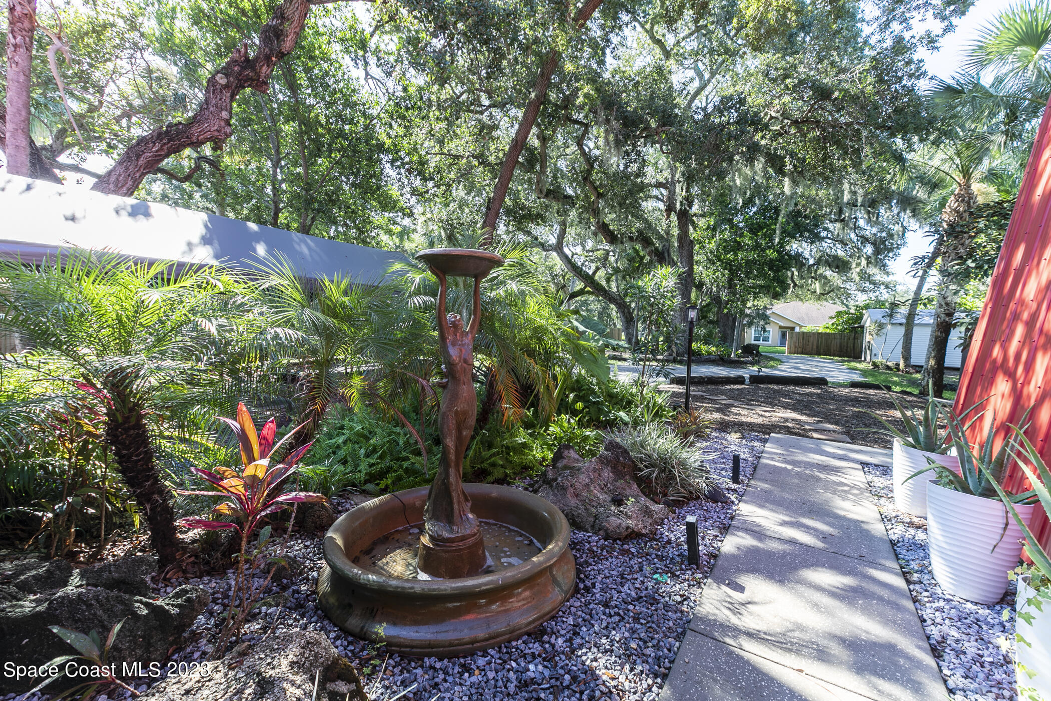 1428 Rose Court Melbourne, FL 32935 - Photo 10 of 78 a view of a backyard with plants and a tree